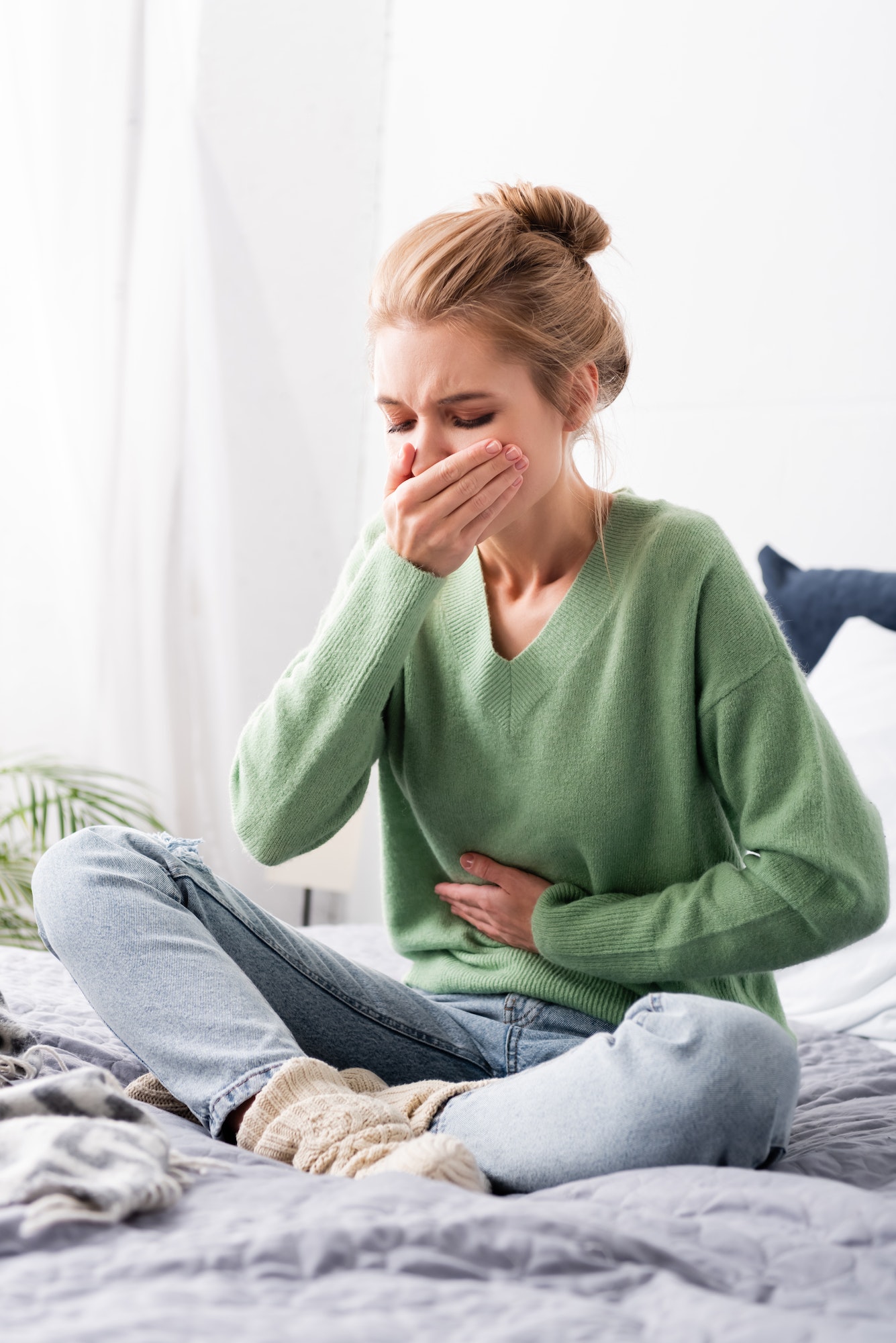 beautiful woman having nausea and sitting on bed