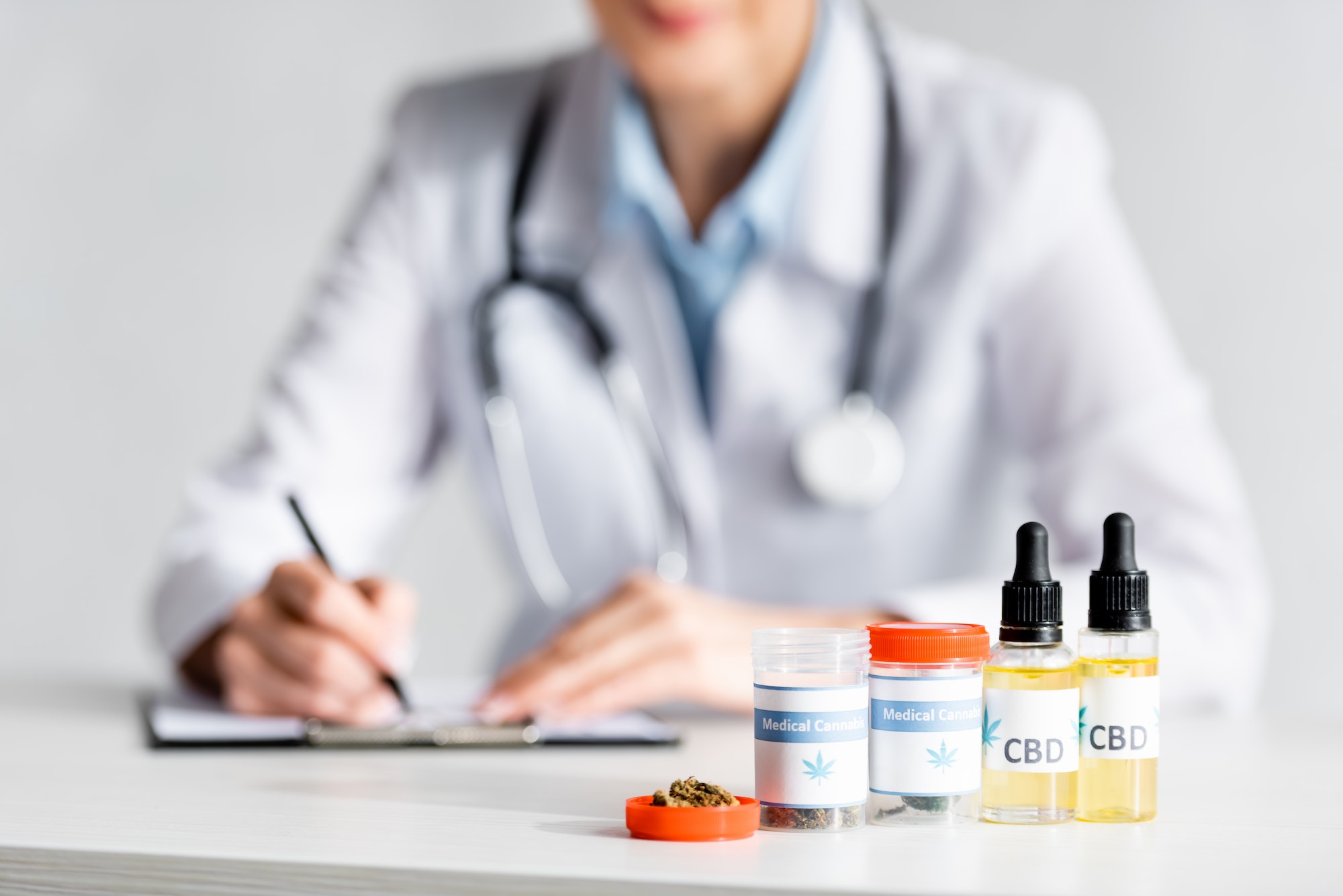 selective focus of dried marijuana, bottles with cbd and medical cannabis lettering near doctor